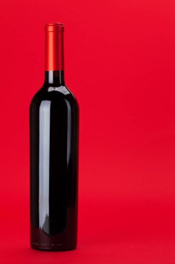 Kırmızı arka planda kırmızı şarap şişesi olan Sevgililer Günü tebrik kartı ve selamlarınız için alanı kopyalayın.