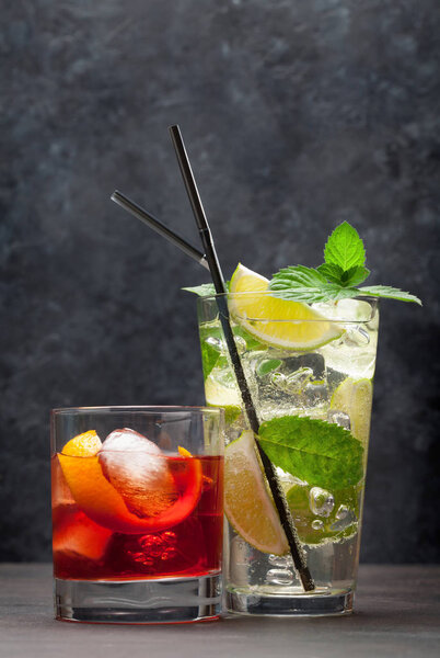 Two classic cocktail glasses on wooden table. Negroni and mojito. With copy space