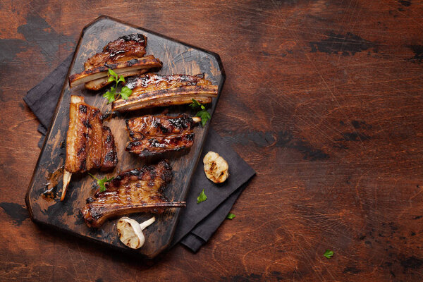 Barbecue beef ribs with bbq sauce sliced on a wooden board. Top view flat lay with copy space