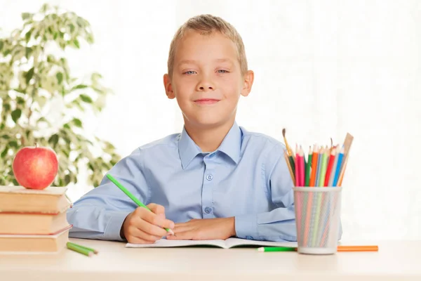 少年はテーブルに座って宿題をしている 初等教育の概念 ストック画像