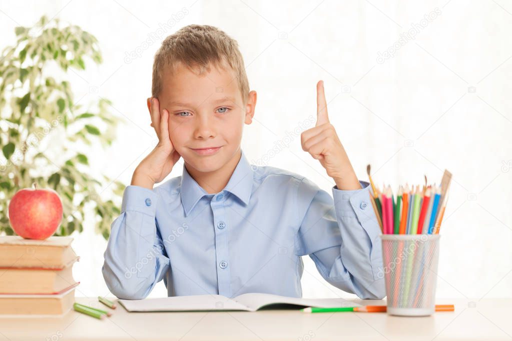Young schoolboy sitting at the table and doing homework. Elementary education concept