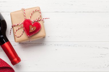 Sevgililer Günü hediye kutusu ve ahşap zemin üzerinde kırmızı şarap şişesi ve selamlarınız için fotokopi alanı. Üst görünüm düzlüğü