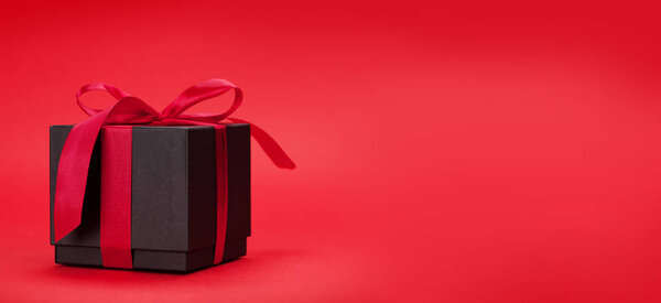 Valentines day greeting card with gift box in front of red background with space for your greetings