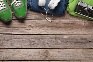 Giysiler ve aksesuarlar. Spor ayakkabı, kot pantolon, kulaklık ve kamera. Her gün için şehir kıyafeti ya da arka planda fotokopi alanı olan bir seyahat tatili. Üst görünüm düzlüğü