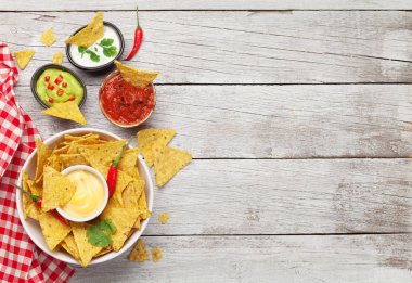 Çeşitli soslu Meksika cipsi. Guacamole, salsa, peynir ve ekşi krema. Üst görünüm düz tahta masa üzerinde kopya alanı ile yatıyordu