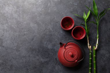 Çaydanlıkta Japon çayı ve taş masada fincanlar. Asya yemekleri konsepti. Üst görünüm düzlüğü kopyalama alanı ile yatıyordu