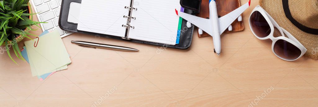 Business travel trip concept. Accessories on desk table. Pc keyboard, passport, notepad, calendar and airplane toy. Top view with copy space. Wide flat lay