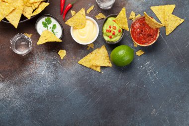 Çeşitli soslu Meksika cipsi. Guacamole, salsa, peynir ve ekşi krema. Üst görünüm düz taş masa üzerinde kopya alanı ile yatıyordu