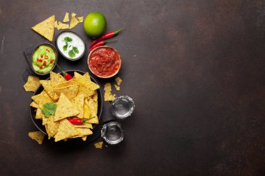 Çeşitli soslu Meksika cipsi - guacamole, salsa ve ekşi krema. Üst görünüm düz taş masa üzerinde kopya alanı ile yatıyordu