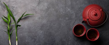 Çaydanlıkta Japon çayı, fincanlar ve taş masada bambu bitkisi. Asya yemekleri konsepti. Üst görünüm düzlüğü kopyalama alanı ile yatıyordu