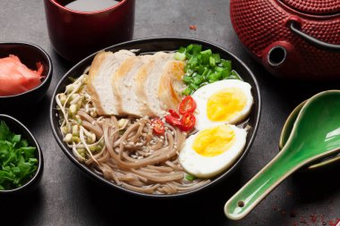 Tavuk, sebze, yumurta ve taş masada bitki çayı ile Asya erişteli ramen çorbası.