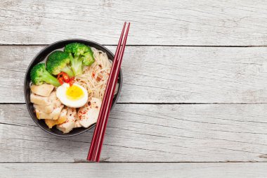 Tavuklu, sebzeli ve ahşap masadaki yumurtalı Asya erişte çorbası. Üst görünüm düzlüğü kopyalama alanı ile yatıyordu