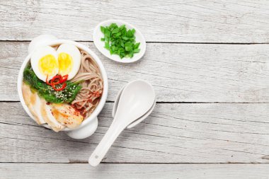 Tavuklu, sebzeli ve ahşap masadaki yumurtalı Asya erişte çorbası. Üst görünüm düzlüğü kopyalama alanı ile yatıyordu