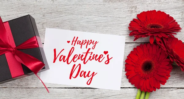 ガーベラの花の花束と木製の背景にギフトボックスとバレンタインデーのグリーティングカード 最上階平面 — ストック写真