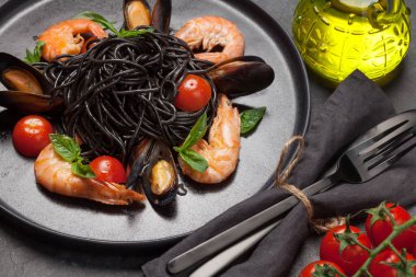 Deniz ürünleri, domates ve fesleğenli siyah spagetti.