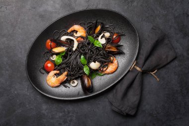 Deniz ürünleri, domates ve fesleğenli siyah spagetti makarna. Üst görünüm düzlüğü