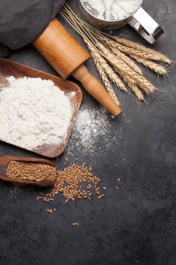 Ekmek malzemeleri. Buğday, un ve mutfak gereçleri taş masada. Ev yapımı yemek konsepti. Üst görünüm düzlüğü kopyalama alanı ile yatıyordu