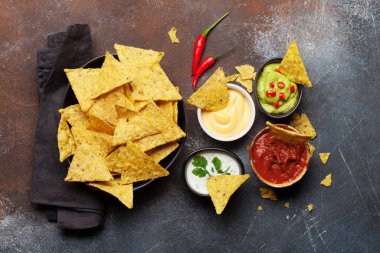 Çeşitli soslu Meksika cipsi. Guacamole, salsa, peynir ve ekşi krema. Üst görünüm düz taş masa üzerinde yatıyordu