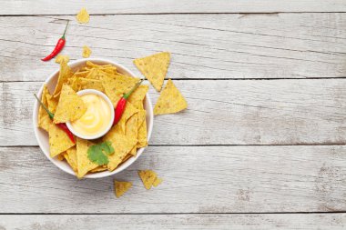 Peynir soslu Meksika cipsi. Üst görünüm düz tahta masa üzerinde kopya alanı ile yatıyordu