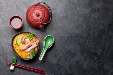 Tom Yum geleneksel Tayland çorbası deniz ürünleri, mantar, hindistan cevizi sütü ve sıcak baharatlı. Yeşil çaydanlık ve kase ile. Kopyalama alanı olan üst görünüm