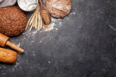 Buğdaylı, unlu ve çatal bıçaklı çeşitli ekmekler. Ev yapımı yemek konsepti. Üst görünüm düzlüğü kopyalama alanı ile yatıyordu