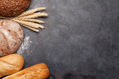 Taş masanın üzerinde buğday ve un bulunan çeşitli ekmekler. Üst görünüm düzlüğü kopyalama alanı ile yatıyordu