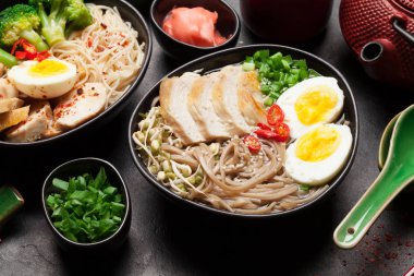 Tavuk, sebze, yumurta ve taştan arkaplanda bitki çayı ile Asya erişteli ramen çorbası.