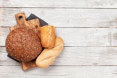 Tahta masada çeşitli ekmekler. Üst görünüm düzlüğü kopyalama alanı ile yatıyordu