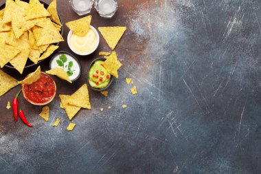 Çeşitli soslu Meksika cipsi. Guacamole, salsa, peynir ve ekşi krema. Üst görünüm düz taş masa üzerinde kopya alanı ile yatıyordu