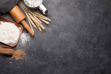 Ekmek malzemeleri. Buğday, un ve mutfak gereçleri taş masada. Ev yapımı yemek konsepti. Üst görünüm düzlüğü kopyalama alanı ile yatıyordu