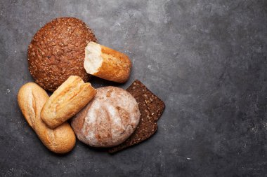 Taş masada çeşitli ekmekler. Üst görünüm düzlüğü kopyalama alanı ile yatıyordu