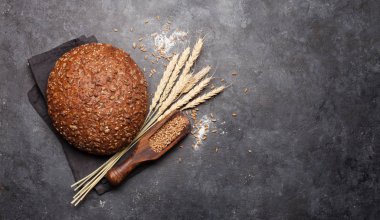 Buğdaylı ekmek ve un taş masada. Ev yapımı yemek konsepti. Üst görünüm düzlüğü kopyalama alanı ile yatıyordu