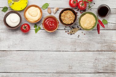 Çeşitli soslar var. Popüler soslar, ketçap, hardal, mayonez ve beyaz ahşap masa. Kopyalama alanı olan üst görünüm. Düz yatıyordu