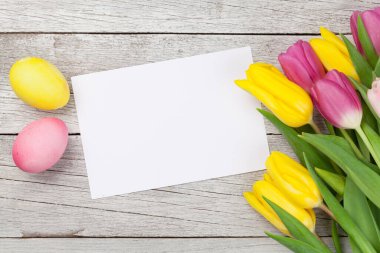 Paskalya tebrik kartı, üzerinde paskalya yumurtaları ve lale çiçekleri var. Üst görünüm düzlüğü kopyalama alanı ile yatıyordu