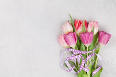 Easter greeting card with colorful tulip flowers over stone background. Top view flat lay with copy space
