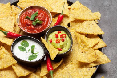 Mexican nachos chips with various sauces - guacamole, salsa and sour cream
