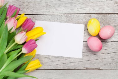 Paskalya tebrik kartı, üzerinde paskalya yumurtaları ve lale çiçekleri var. Üst görünüm düzlüğü kopyalama alanı ile yatıyordu