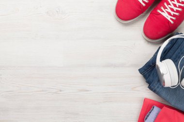 Giysiler ve aksesuarlar. Spor ayakkabı, kot pantolon ve kulaklık. Her gün için şehir kıyafeti ya da arka planda fotokopi alanı olan bir seyahat tatili. Üst görünüm düzlüğü