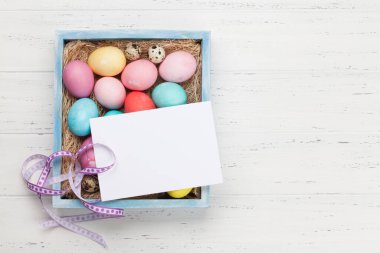 Easter greeting card with colorful easter eggs on wooden background. Top view flat lay with space for your greetings