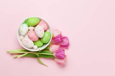 Paskalya tebrik kartı, pembe arka planda paskalya yumurtaları ve lale çiçekleri. Üst görünüm düzlüğü kopyalama alanı ile yatıyordu