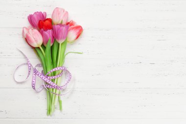 Easter greeting card with tulip flowers over wooden background. Top view flat lay with space for your greetings