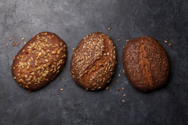 Различные домашний хлеб с семенами на каменном столе. Квартира с видом сверху

