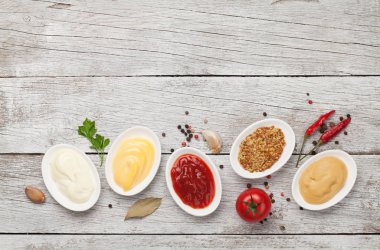 Çeşitli soslar var. Popüler soslar, ketçap, hardal, mayonez ve beyaz ahşap masa. Kopyalama alanı olan üst görünüm. Düz yatıyordu