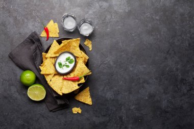 Ekşi krema soslu Meksika cipsi ve tekila. Üst görünüm düz taş masa üzerinde kopya alanı ile yatıyordu