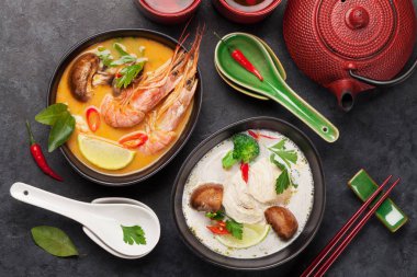 Tom Yum ve Tom Kha geleneksel deniz ürünleri, tavuk, mantar, hindistan cevizi sütü ve sıcak baharatlı Tayland çorbaları. Yeşil çaydanlık ve kase ile. Üst görünüm