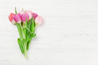 Easter greeting card with tulip flowers over wooden background. Top view flat lay with space for your greetings