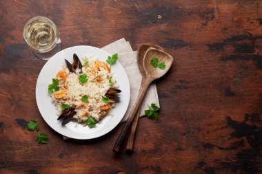 Karidesler, karides, midye ile lezzetli deniz ürünleri risotto. Parmesan peyniri ve maydanoz giymiş. Beyaz şarap camı ve kopya alanı ile üst görünüm