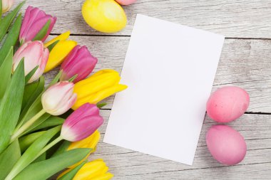 Paskalya tebrik kartı, üzerinde paskalya yumurtaları ve lale çiçekleri var. Üst görünüm düzlüğü kopyalama alanı ile yatıyordu
