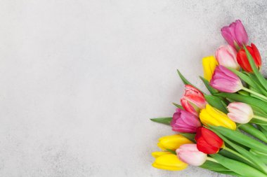Easter greeting card with tulip flowers over stone background. Top view flat lay with space for your greetings