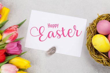 Paskalya tebrik kartında paskalya yumurtaları ve lale çiçekleri var. Üst görünüm düzlüğü